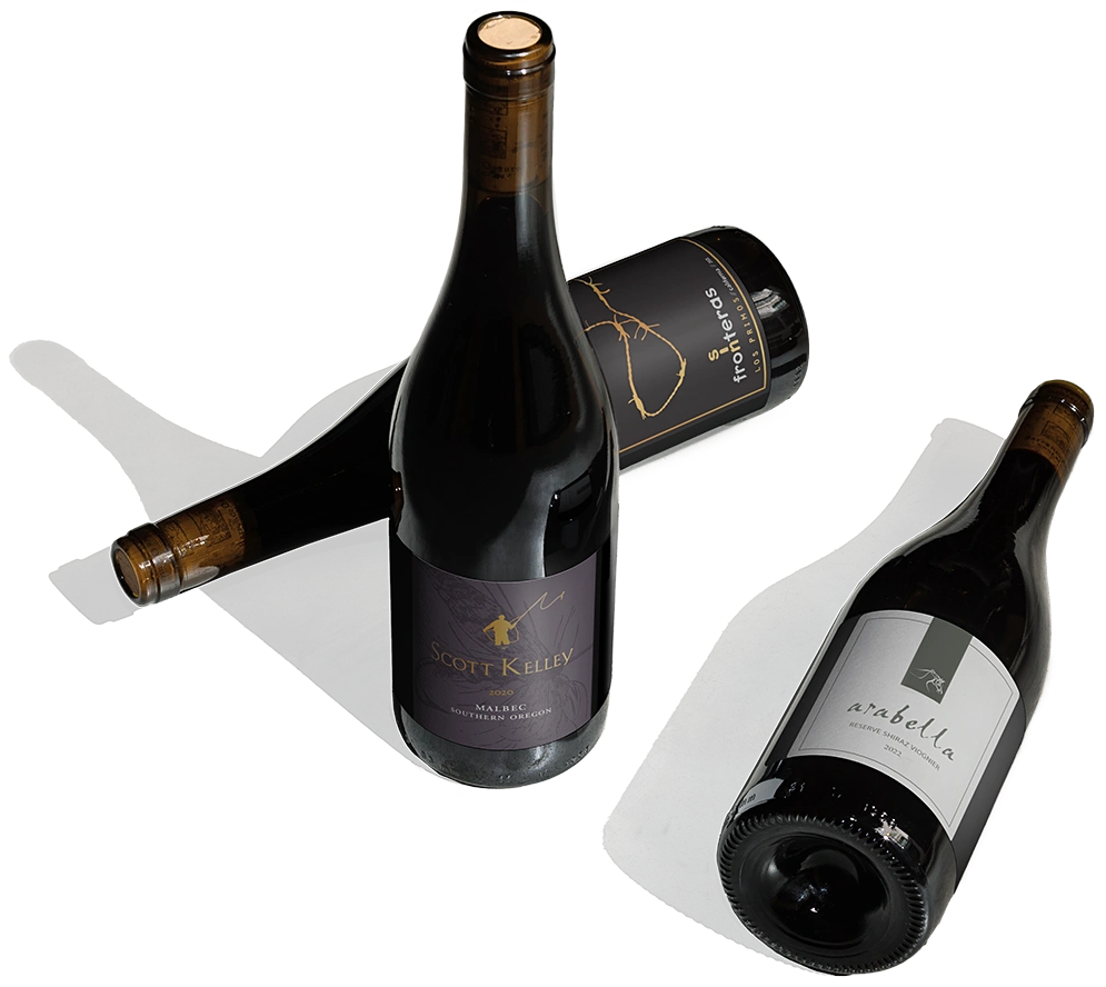 Three bottles of wine against a light grey background, two standing up and one lying down.